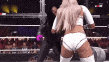 a woman in a white outfit is wrestling a man in a black suit in a wrestling ring .