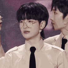 a young man wearing glasses and a tie stands next to another man