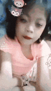 a little girl wearing a pink shirt with a hello kitty sticker on her head .