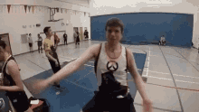 a group of men are playing basketball in a gym and one of them is wearing a overwatch shirt .
