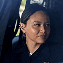 a woman in a police uniform is looking out of a window