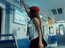 a woman in a red hat is riding a train with an advertisement for domino 's pizza on the wall