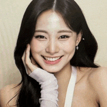 a woman with long black hair is smiling with her hand on her chin