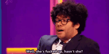 a man with curly hair is wearing glasses and a suit and tie .