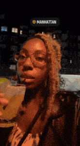 a woman holding a drink with a manhattan sticker on her face