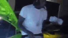 a blurry picture of a man in a white shirt standing in front of a green plant .