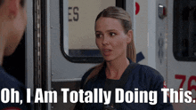 a woman is standing in front of an ambulance with the words oh i am totally doing this