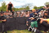 a man stands on a fence with a crowd behind him and the word ufc is on the fence