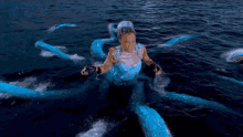 a woman in a blue dress is surrounded by blue tentacles in the ocean
