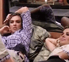 a man and a woman are laying on a couch with their heads down .