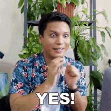 a man in a floral shirt is making a funny face and saying yes