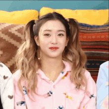 a girl with pigtails is wearing a pink shirt with animals on it