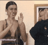 a woman in a green dress applauds while another woman looks on