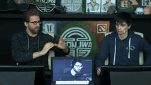 two men are sitting in front of a screen that says on jiwa