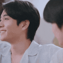 a man in a white shirt is smiling and looking at another man