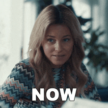 a woman in a multicolored shirt says " now "