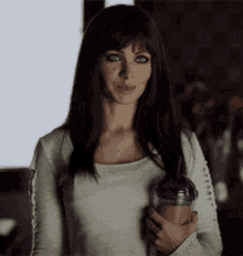 a woman is holding a cup of coffee in her hand