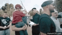 a man is holding a little boy in his arms while a group of men are standing around .