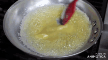 a frying pan with a red spoon in it and the words made in animatica on the bottom right