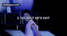 a man is dancing on a stage with the words `` oh wait he 's hot '' behind him .
