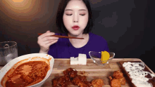 a woman is eating a bowl of food with chopsticks .