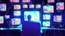 a man is sitting in front of a bunch of monitors that are glowing in the dark