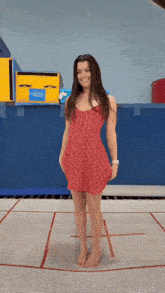 a girl in a red dress stands on a trampoline