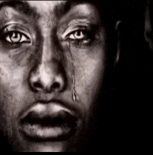 a black and white photo of a woman 's face with a tear coming out of her eye .