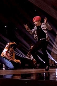 a man with red hair is dancing on a stage with a man wearing a sweater that says ' dubai '