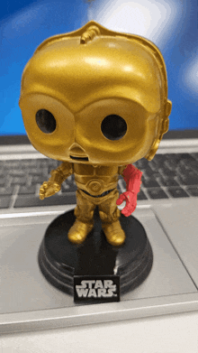 a gold star wars funko pop is sitting on a laptop