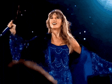 a woman in a blue dress holds a microphone