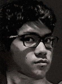 a young man wearing glasses is looking at the camera