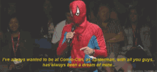 a man in a spiderman costume is speaking into a microphone at comic con