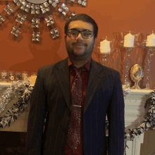 a man wearing a suit and tie stands in front of a fireplace