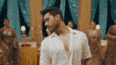 a man in a white shirt is dancing in front of a group of women in a room .