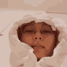 a young man wearing glasses and a white hoodie is taking a selfie .