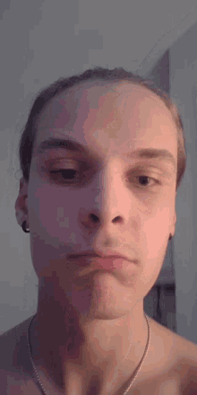 a young man with a necklace around his neck is making a face