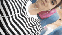 a woman wearing a black and white striped shirt is laying on a bed with headphones on .