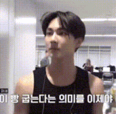 a man wearing a black tank top is standing in a room with chinese writing on the wall .