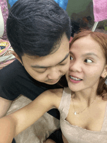 a man and a woman are posing for a picture and the woman is wearing braces