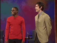 a man in a red sweater is talking to another man in a green suit