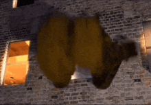 a large stuffed animal is flying through the air in front of a brick building .