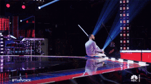 a nbc advertisement for the voice shows a man on stage