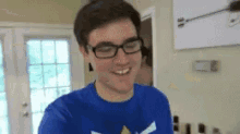 a man wearing glasses and a blue shirt smiles