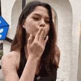 a woman covering her mouth with her hand in front of a domino 's sign