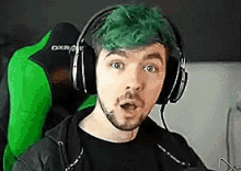 a man with green hair is wearing headphones .