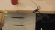 a person is measuring something with a tape measure while sitting at a desk .