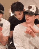 a group of young men are sitting next to each other and one of them is wearing a hat .