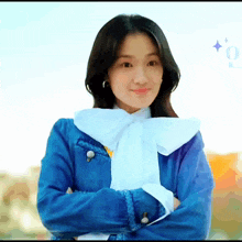 a woman wearing a blue jacket and a white scarf is smiling