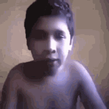 a boy without a shirt looks at the camera